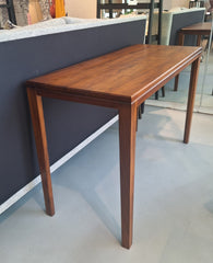 A rectangular wooden console table with a grooved line between the top and the legs, having a natural finish.