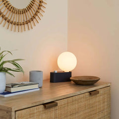 Alumina Lamp Charcoal with a matte-porcelain sphere-shaped shade and a charcoal black base, featuring a dimmable LED bulb, by Tala