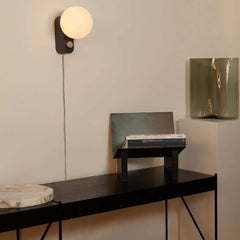 Alumina Lamp Charcoal with a matte-porcelain sphere-shaped shade and a charcoal black base, featuring a dimmable LED bulb, by Tala