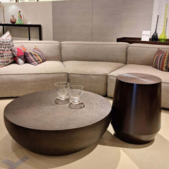 A drum-shaped Congo Coffee Table with a bronze finish and hammered aluminium texture.