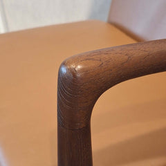 Close-up of Cynthia Armchair Tan Leather teak armrest with a blurred background