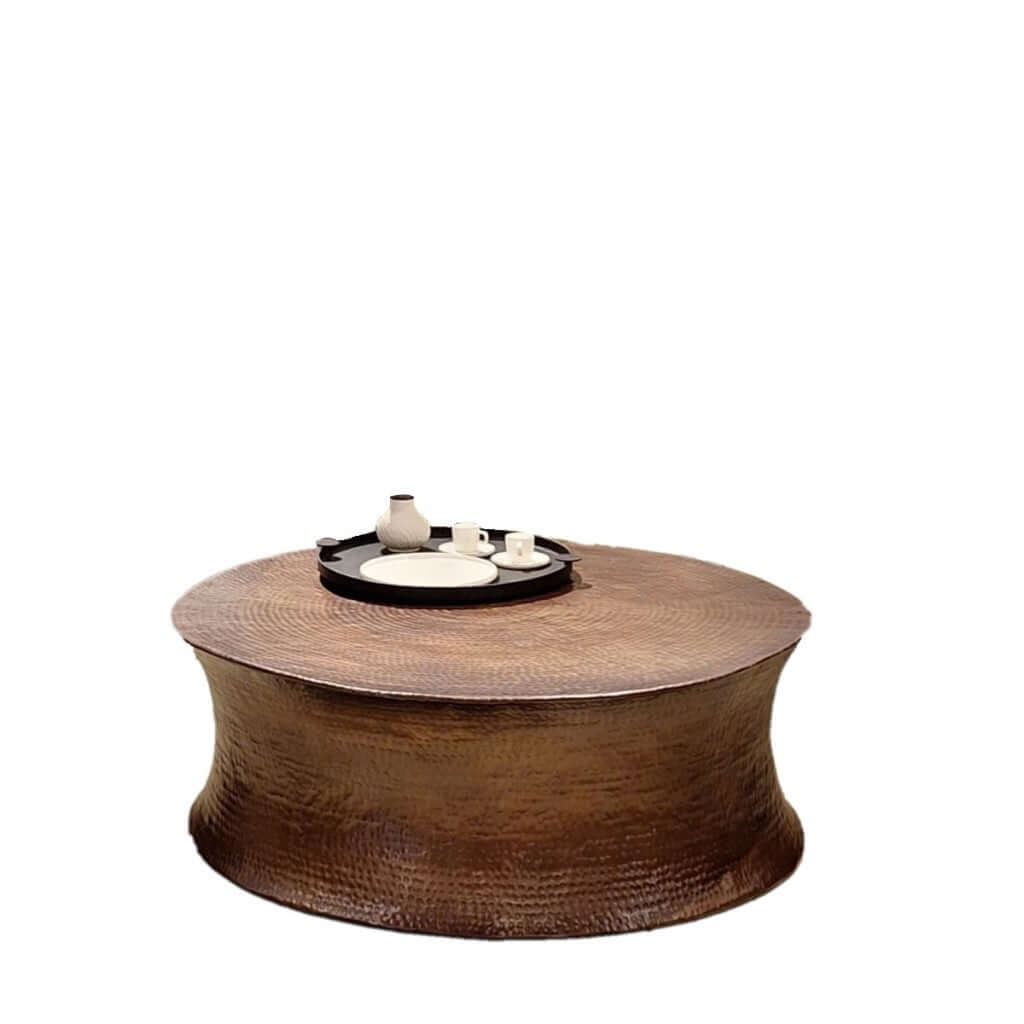 A unique Drum Coffee Table with hammered patterns, finished in oil brass matt, displaying a decorative tray on its surface.