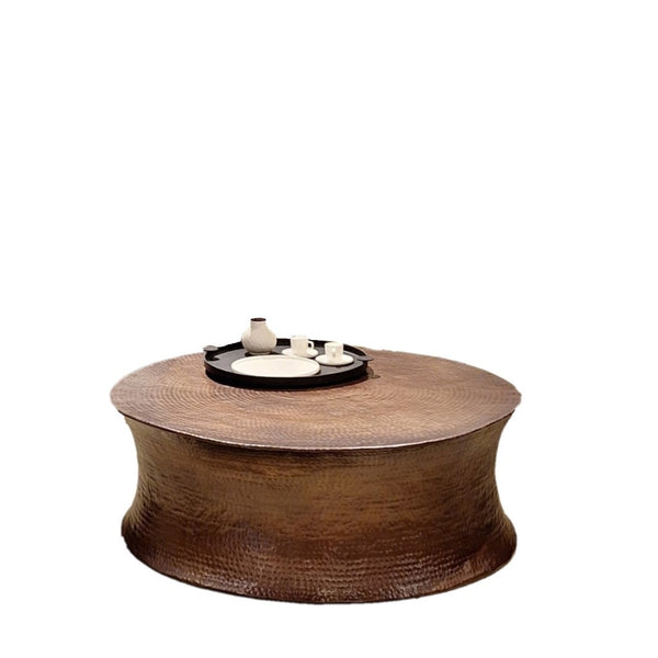 A unique Drum Coffee Table with hammered patterns, finished in oil brass matt, displaying a decorative tray on its surface.