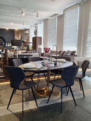 Oval-shaped aluminium Eclipse Dining Table with blackish bronze finish top and antique brass finish base 