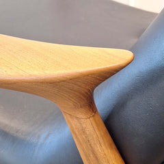 Close-up of Eyes Lounge Chair armrest against a black leather seat