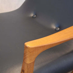 Close-up of Eyes Lounge Chair armrest against a black leather seat