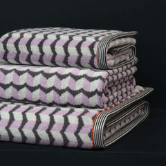 A family of pink grey white patterned towels stacked, includes a Finchley Hand Towel, a bath towel and a bath sheet, by Margo Selby