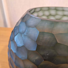 Fjord Vase 24cm in deep teal-blue frosted glass, its entire surface covered in dense small hammered cells that scatter light like sunlight breaking across cold, mineral-rich water.