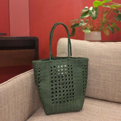 Dragon Diffusion Grace Cannage Forest woven leather handbag on a beige couch 