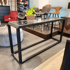 A contemporary console table with a solid ash wood frame in charcoal color and clear tempered glass top.