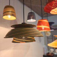 A green pendant light with a telephone wire lampshade, hanging from a black fixture.