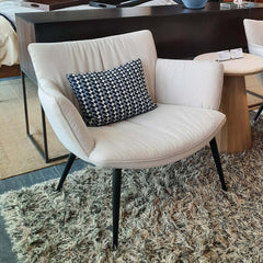 A beige upholstered lounge chair with black metal legs.