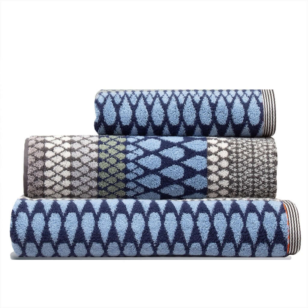 Set of three blue grey patterned towels stacked, a hand towel, a bath towel and a Kensal Bath Sheet by Margo Selby