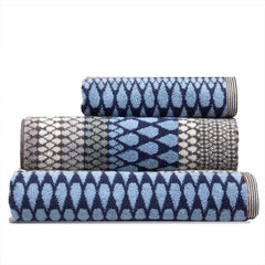 Set of three blue grey patterned towels stacked, a Kensal Hand Towel, a bath towel and a bath sheet, by Margo Selby
