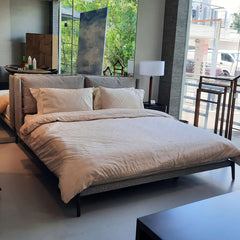 Upholstered king bed with metal legs and grey fabric, pictured without a footboard