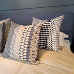Margo Selby Etch Square Cushion and Knight Square Cushion on a bed