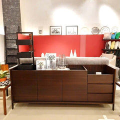 A dark brown Mora Sideboard with three doors on the left side and three drawers on the right side, made of smoked eucalyptus veneer on mdf with a glass top and stainless steel base.