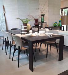 A rectangular charcoal-finished solid timber dining table with four asymmetrically positioned corner legs.