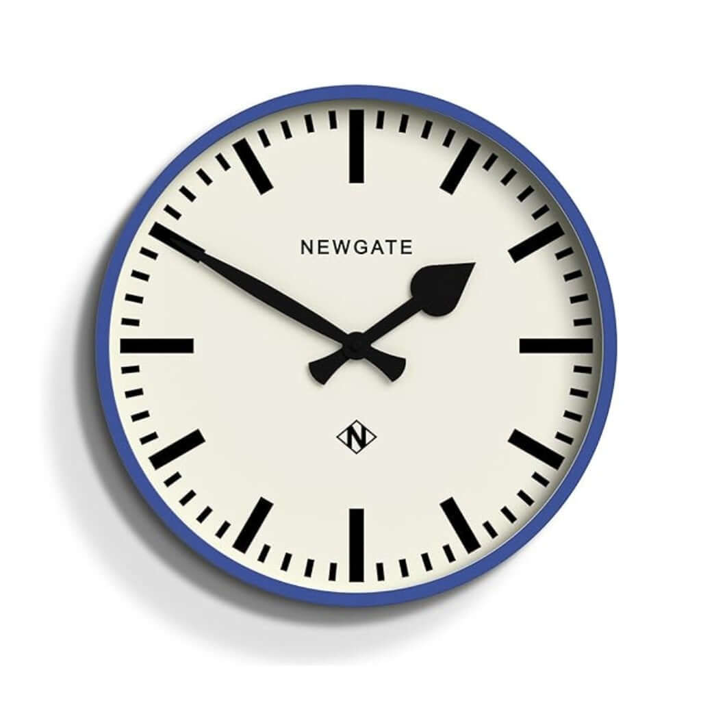 Newgate Railway Wall Clock Blue with a blue silicone case and a white dial. The clock hands are black, and the design includes bold markers and a glass lens.
