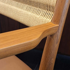 Close-up of teak armrest on Roxita Armchair Danish Cord Natural with woven cord backrest and tan leather cushion
