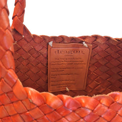 Close Up of Dragon Diffusion Santa Croce Big Orange with asymmetric leather straps and a woven basket-like design.