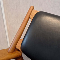 Close up of a Sawbuck Lounge Chair with black leather backrest