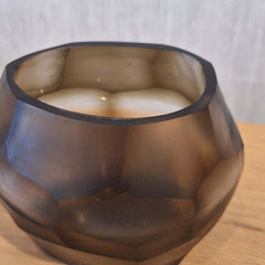 Sunhive Tealight Holder 8cm in warm smoky taupe frosted glass, its compact form wrapped in angular faceted cells that catch and hold the light with a quiet, burnished warmth.