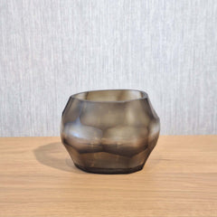 Sunhive Tealight Holder 8cm in warm smoky taupe frosted glass, its compact form wrapped in angular faceted cells that catch and hold the light with a quiet, burnished warmth.