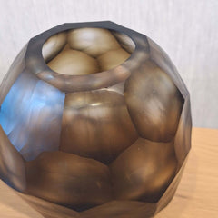 Sunhive Vase 16cm in warm smoky taupe frosted glass, its compact form wrapped in angular faceted cells that catch and hold the light with a quiet, burnished warmth.