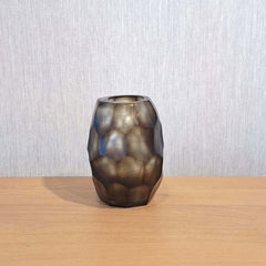 Sunhive Vase 16cm in warm smoky taupe frosted glass, its compact form wrapped in angular faceted cells that catch and hold the light with a quiet, burnished warmth.