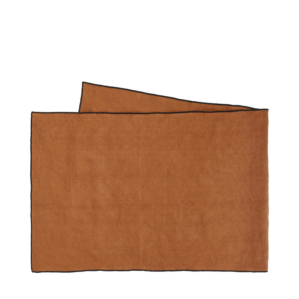 A ginger-colored, linen Table Runner Ginger with a black cordon stitch edge, by ASA selection
