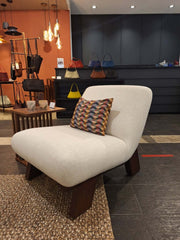 An armless lounge chair with a dark wood base and off-white fabric upholstery.