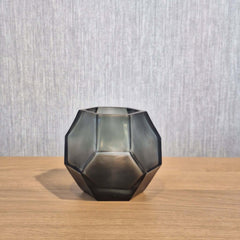 Tundra Tealight Holder 9cm in cool silver-grey frosted glass, its geometric facets casting a soft, fractured glow when lit from within.