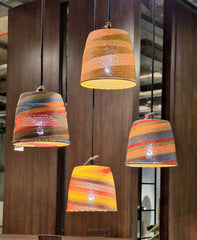 A collection of pendant light made of woven telephone wire, with a conical shape, hanging from a black cord.