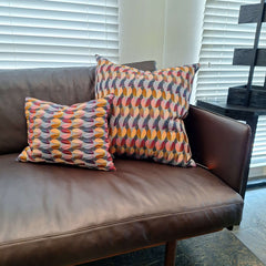 Margo Selby Wisley Cushions with a multicolored geometric pattern on a leather sofa