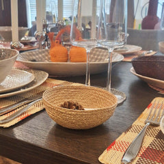 Dining table setting with handmade Iraca Small Bowl Plain Toasted, glasses, and cutlery on a wooden table.