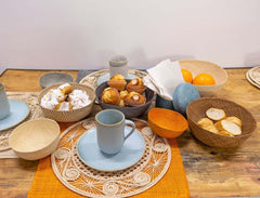 Table setting with handmade Iraca Bowls of bread, pastries and fruits.