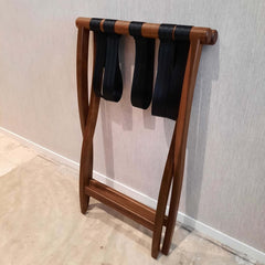A solid walnut luggage rack with heavy duty nylon straps, foldable design.