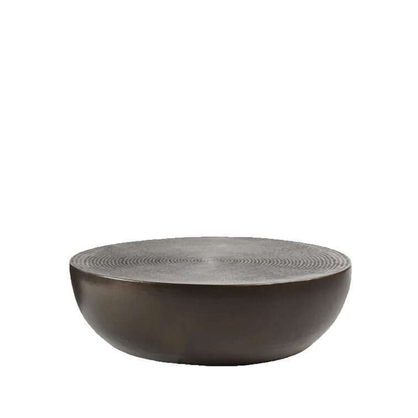 A drum-shaped coffee table with a bronze finish and hammered aluminium texture.
