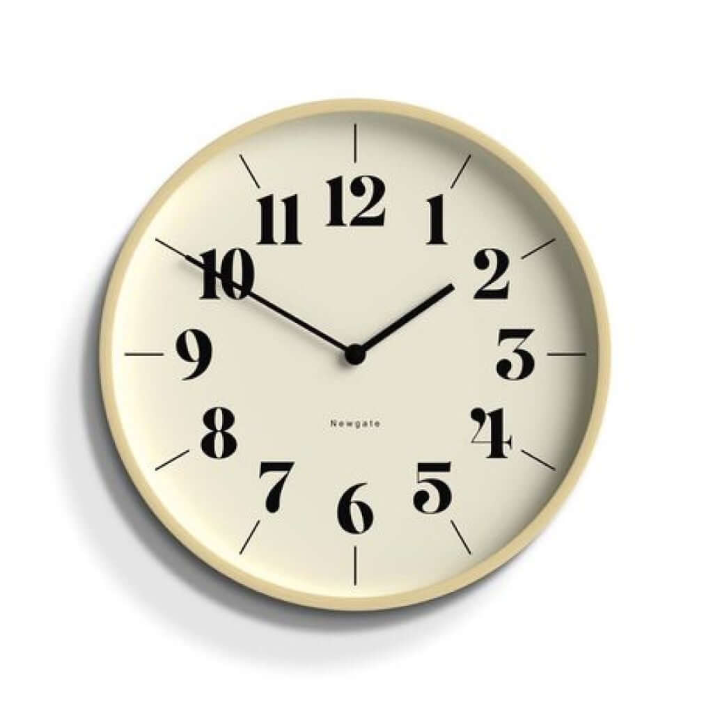 A Newgate Mr Clarke Wall Clock Pale Wood Hopscotch Dial with a pale plywood case and a numerical hopscotch dial with metal hands and a glass lens, displaying the time.