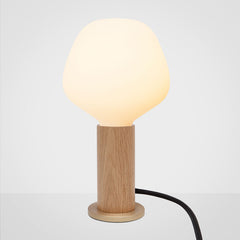 A cylindrical oak wood table lamp base with a brass in-line dimmer, featuring a smooth finish and a tactile dimmer switch, by Tala