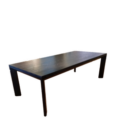A modern rectangular dining table made of solid ash with a charcoal finish, featuring a mitre joint at the corners and stained legs.